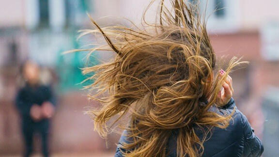 Eine Windböe wirbelt die Haare einer Frau auf dem Eisernen Steg durcheinander.