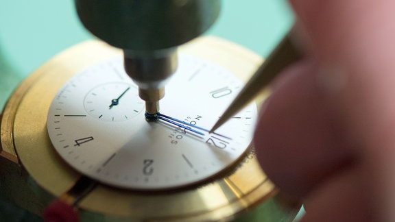 Ein Uhrmacher justiert in der Uhrenmanufaktur Nomos die Zeiger des Uhrenmodells Tangente 33.
