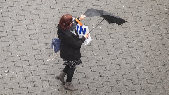 Der Regenschirm einer Frau wird von einer Windböe erfasst.