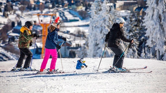 Menschen in bunten Skianzügen stehen an einem Schneehang und fahrne jedne Moment ins Tal richtung Oberwiesenthal. Zum Winterferienstart 2020 war am fichtelberg jedeMenge los. 