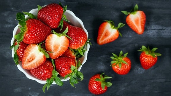 Draufsicht auf Erdbeeren in einer Schale mit frischen reifen ganzen und halbierten Erdbeerfrüchten.