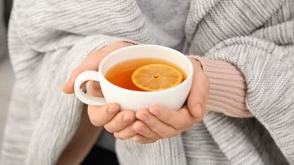 Eine Frau hält eine Tasse Tee in den Händen.