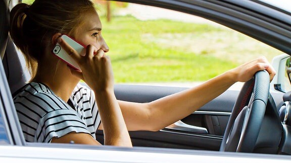 Eine junge Frau telefoniert im Auto