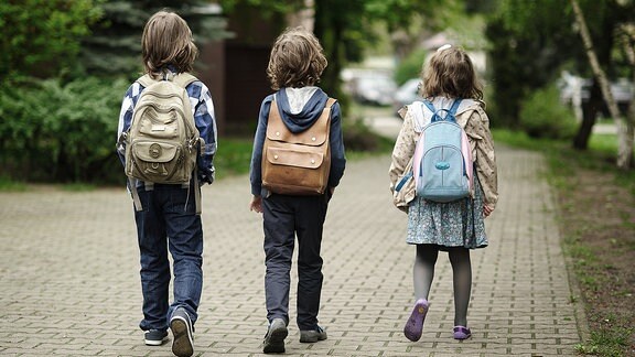 Drei Kinder auf dem Weg zur Schule.