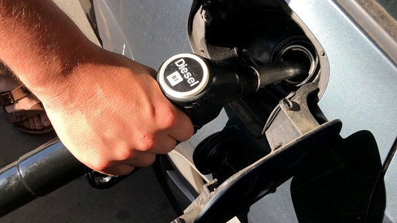 Ein Mann betankt an einer Tankstelle sein Auto mit Diesel