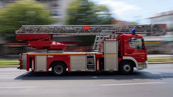 Ein Feuerwehrauto fährt mit Blaulicht zu einem Einsatz (Aufnahme mit Langzeitbelichtung und Mitzieher-Effekt).