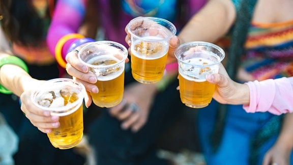 Vier volle Becher mit Bier, die von jungen Frauen gehalten werden