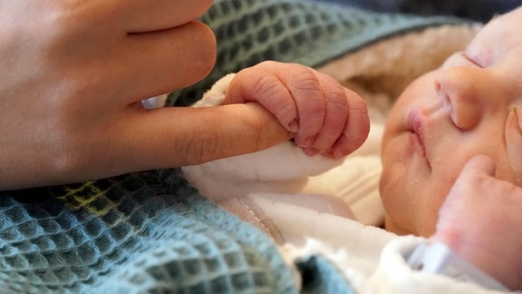 Der am 1. Mai geborene Säugling Henry gähnt und greift einen Finger seiner Mutter Kristin in einem Zimmer der Geburtshilfestation in der Frauenklinik im Städtischen Krankenhaus Kiel.