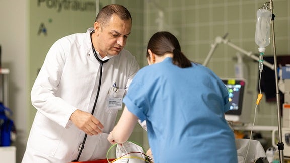 Ein Oberarzt betreut in einem Schockraum der Notaufnahme einen Patienten gemeinsam mit einer Krankenschwester.