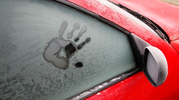 Ein Handabdruck auf einer gefrorenen Autoscheibe.