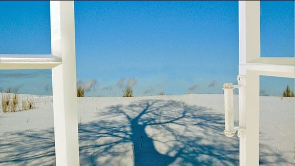 Ein geöffnetes Fenster mit Blick auf eine Winterlandschaft und stahlblauen Himmel.