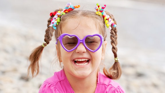 Ein Mädchen trägt eine Sonnenbrille.