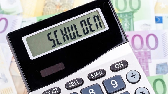 Das Wort "Schulden" steht auf einem Taschenrechner, der auf Euro-Banknoten liegt.