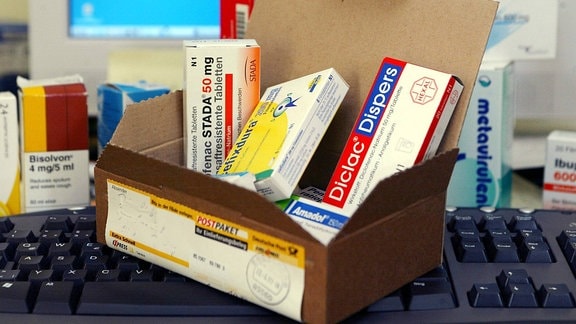 Ein geöffnetes Paket mit verschiedenen Medikamenten steht auf einer Computertastatur. 