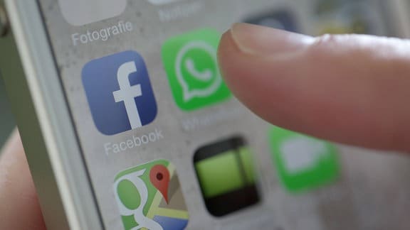 Finger weist auf ein WhatsApp-Icon auf einem Smartphone-Display