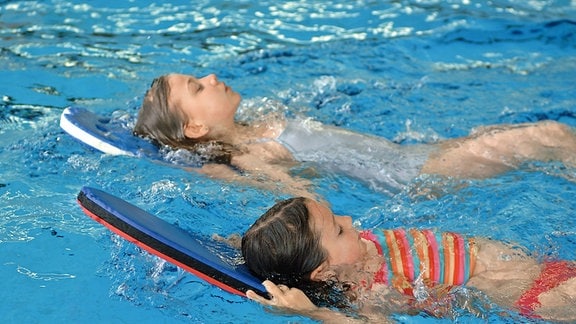 Schwimmunterricht: Kinder mit Schwimmhilfe im Wasser