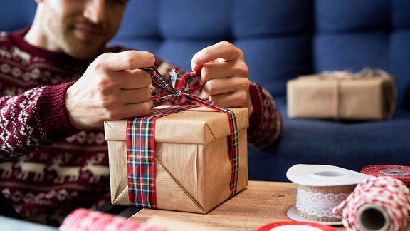 Ein Mann verpackt ein Geschenk