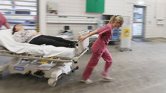 Patientin wird von Notfallpersonal auf rollbarer Trage in Notaufnahme gezogen