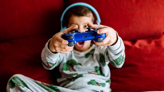 Junge im Schlafanzug trägt während eines Videospiels Kopfhörer