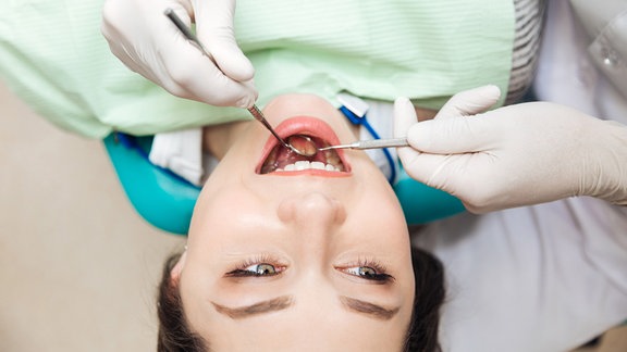 Patientin mit geöffnetem Mund während einer Zahnuntersuchung